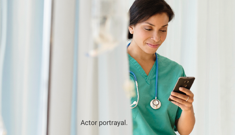 Actor portrayal of female nurse in green scrubs looking at her cellphone
